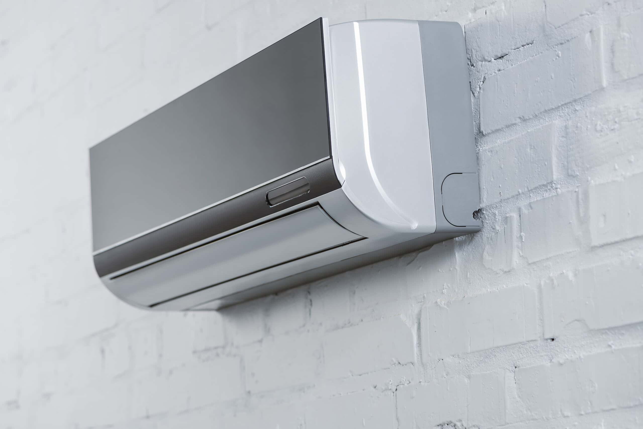 close-up shot of grey air conditioner hanging on white brick wall Efficient Home Heating