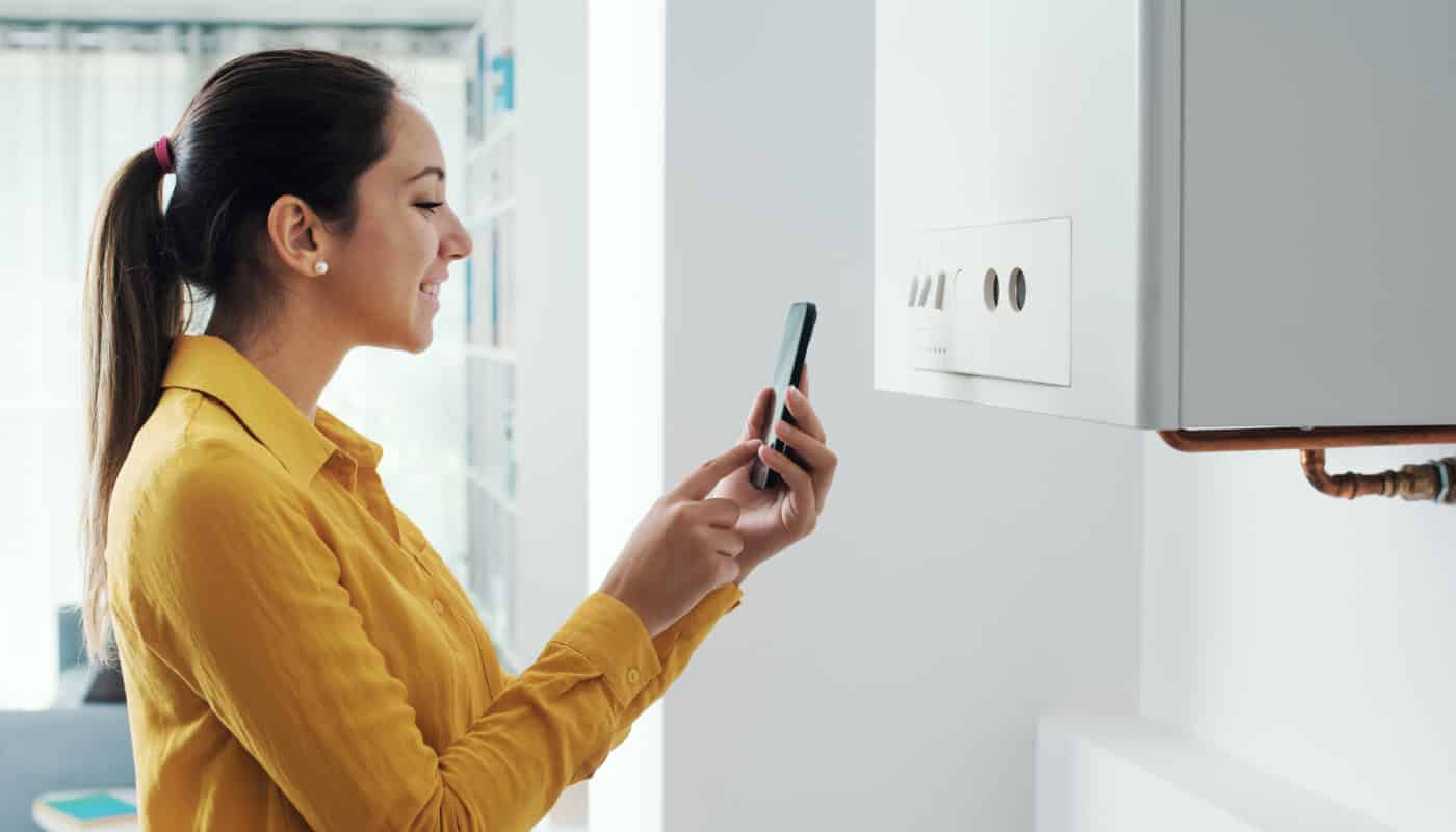 woman-using-smartphone-to-manage-home-heating Smart Hot Water Storage: Beyond the Geyser for South African Homes